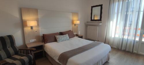a hotel room with a bed and a chair at Hotel Uhainak in Hendaye