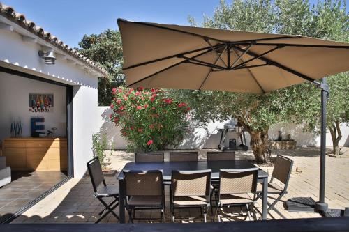 - une table et des chaises sous un parasol sur la terrasse dans l'établissement Villa Escale en Re, à Sainte-Marie de Ré