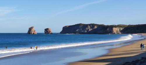 people walking on a beach with rocks in the water at Hotel Uhainak in Hendaye