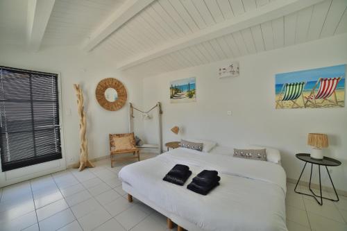 ein Schlafzimmer mit einem Bett mit zwei schwarzen Handtüchern darauf in der Unterkunft Villa Escale en Re in Sainte-Marie-de-Ré