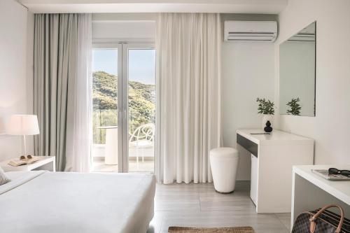 a white hotel room with a bed and a balcony at Racconto Boutique Design Hotel (Adults Only) in Parga