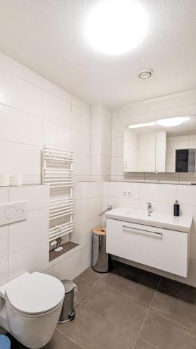 a white bathroom with a toilet and a sink at Ferienwohnung Landliebe in Schwangau