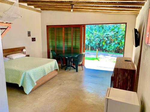 um quarto com uma cama, uma mesa e uma janela em Prumirim Camping & Chalés em Ubatuba