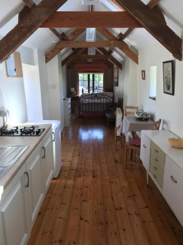 a kitchen with white cabinets and a wooden floor at Ancaire Studio in Schull