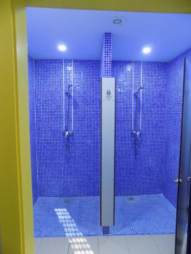 y baño con ducha de azulejos azules. en Albergue de São Bento en Caminha