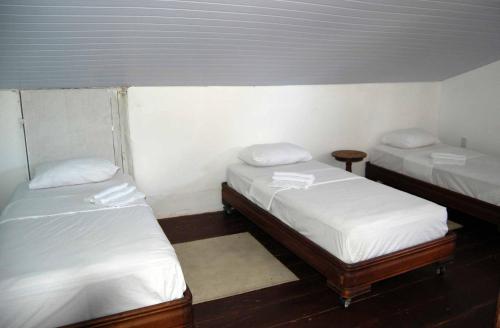 two beds in a small room with white sheets at Hostel Nossa Sra de Lourdes in Salvador