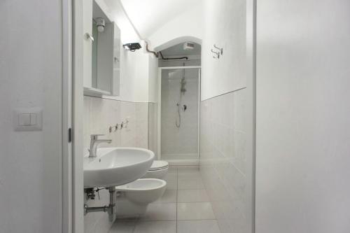 La salle de bains blanche est pourvue d'un lavabo et de toilettes. dans l'établissement Casa Paola, à Levanto