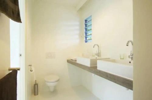 a white bathroom with two sinks and a toilet at Idyllic Curacao Home with Stunning Views in Willemstad