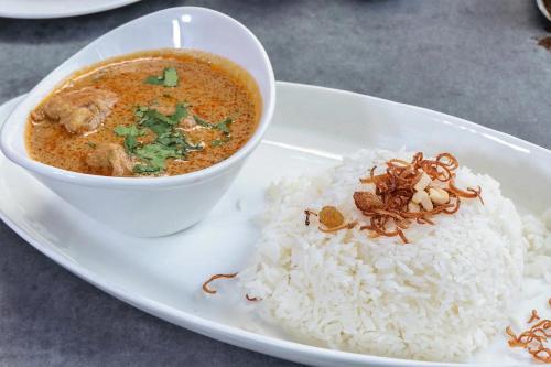 a plate of food with a bowl of soup and rice at Hiddenvalley Stays - Nethra in Madikeri