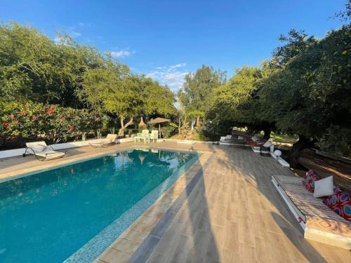 - une piscine dans une cour avec des chaises et des arbres dans l'établissement Villa Tigmin Eden, à El Arba