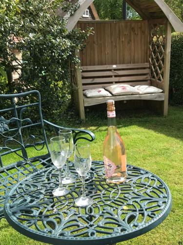 a table with a bottle of wine and glasses on it at Idyllic Stratford upon Avon cottage in Shottery