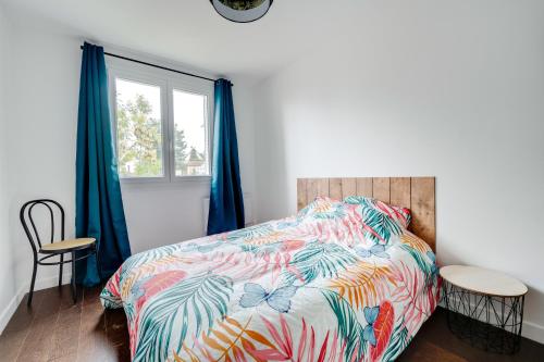 Un dormitorio con una cama con un edredón colorido y una ventana en Le Petit Calypso, en Nancy
