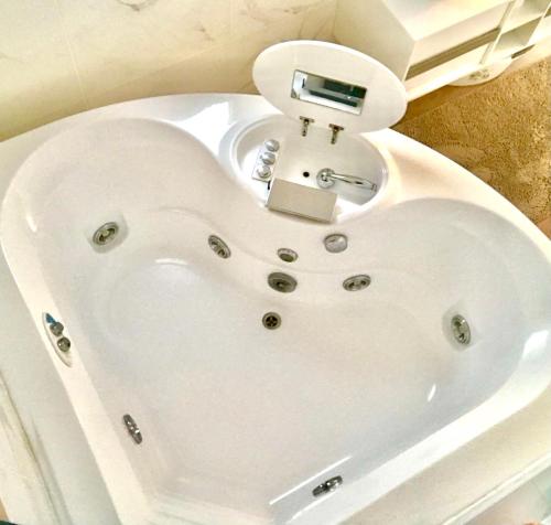a white bath tub with a clock on top of it at Stanza e idromassaggio, con extra fee, in delizioso appartamento in Ferrara