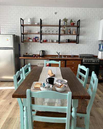 cocina con mesa de madera con sillas y nevera en CASA CATALINA en Rafaela