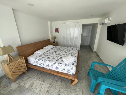 a bedroom with a bed and a blue chair at Hermosos Apartamentos Frente Al Mar in San Andrés