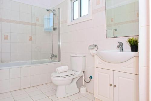 La salle de bains blanche est pourvue de toilettes et d'un lavabo. dans l'établissement Villa Ourania, à Protaras