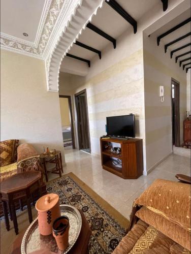 sala de estar con sofá y TV en Appartement en résidence avec parking en Marrakech
