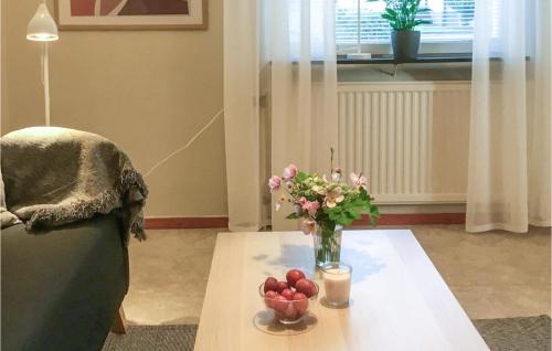 une table avec un vase de fleurs et de fruits sur elle dans l'établissement Stunning Apartment In Kvillsfors With Kitchen, à Kvillsfors