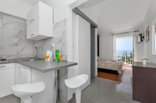 a white kitchen with a counter and a living room at Villa NIKA & KARLO Makarska in Makarska