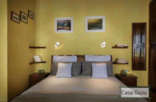 een slaapkamer met een groot bed met gele muren bij PienzaLettings "Casa Gioia" in Pienza
