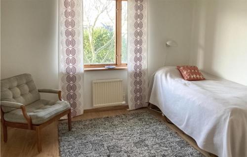 a bedroom with a bed and a chair and a window at Awesome Home In Simrishamn With House Sea View in Simrishamn