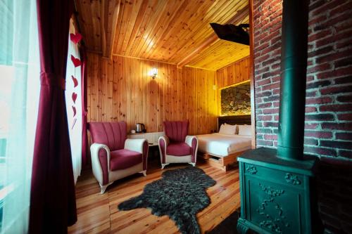 a room with a fireplace and a bed and a room with a stove at Abant Yayla Dağevi in Dereceören