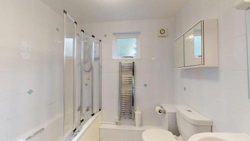 a white bathroom with a toilet and a sink at 26 Strawberry Hill, Tolroy Manor in Hayle