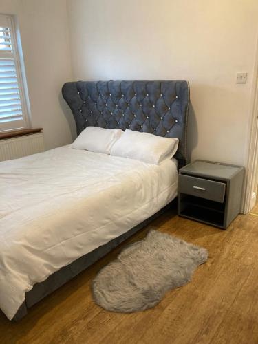 a bedroom with a bed with a blue headboard and a rug at Green Villa in Hickleton