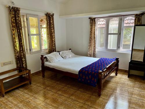 ein Schlafzimmer mit einem Bett in einem Zimmer mit Fenstern in der Unterkunft Hiddenvalley Stays - Nethra in Madikeri