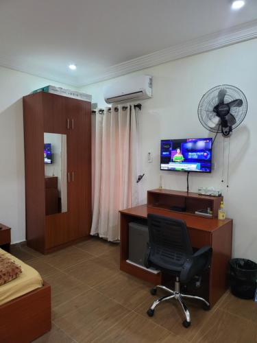 a bedroom with a desk and a chair and a tv at BDA APARTMENT - Netflix, Free Wi-Fi, PlayStation 4, Kitchen, Supermarket, Pharmacy, Laundry & 24hours Electricity in Abuja
