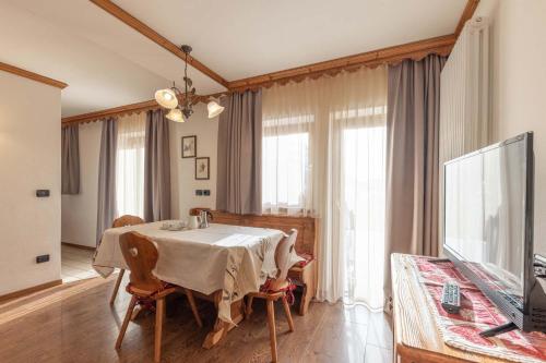 una sala da pranzo con tavolo e TV di Residence Adler a San Martino di Castrozza