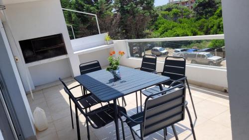 una mesa con sillas y un jarrón de flores en el balcón en el Departamento Las Gaviotas en el Balneario Mar Azul
