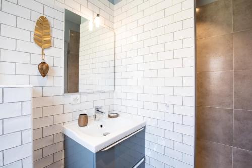 W białej łazience znajduje się umywalka i lustro. w obiekcie La COLOC w mieście Lacanau