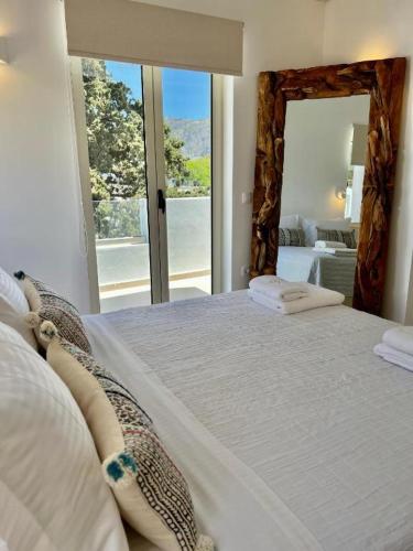 a bedroom with a large bed with a large window at Thealos Santorini ( close to square) in Pirgos