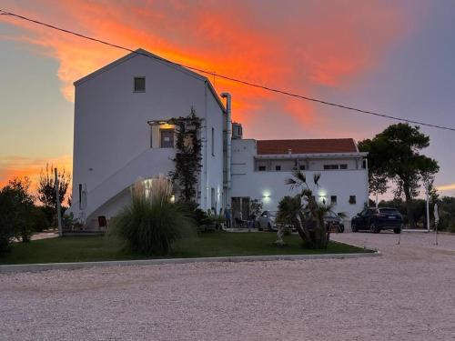 un edificio bianco con un tramonto sullo sfondo di Agriturismo Masseria Cannella a Lesina