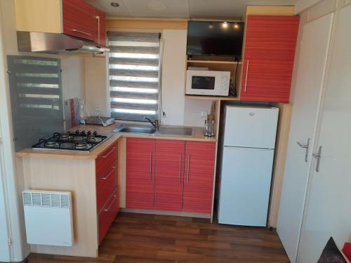 a small kitchen with red cabinets and a white refrigerator at La Muela in Cádiz