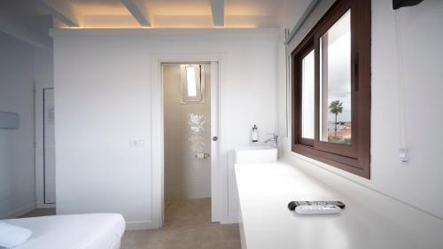 a white bathroom with a sink and a mirror at Castell de Lô in Cala'n Porter