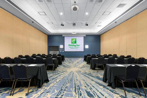 a conference room with tables and chairs and a screen at Holiday Inn Melbourne-Viera Conference Ctr by IHG in Melbourne