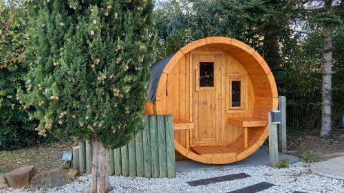 uma sauna de madeira num jardim junto a uma árvore em Adorable Guest House avec balnéo et piscine em Olonne-sur-Mer