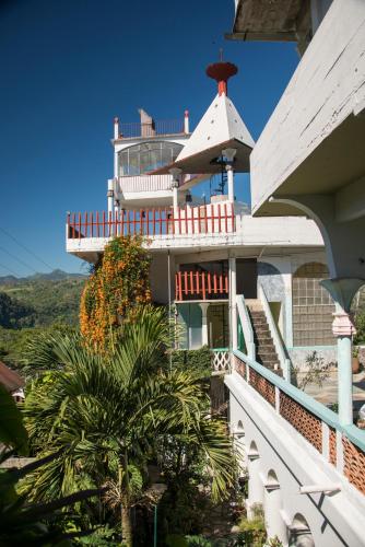 a building with a balcony and palm trees in front of it at Posada El Castillo xilitla in Xilitla