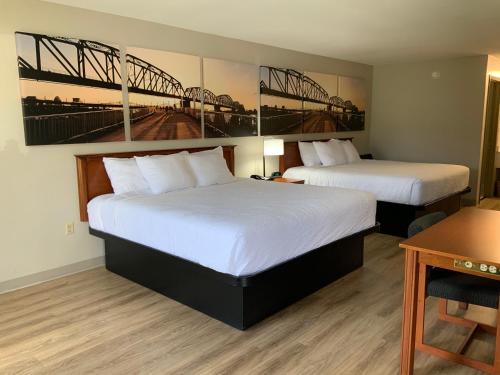 a hotel room with two beds and a bridge painting on the wall at Days Inn by Wyndham Lake City I-10 in Lake City