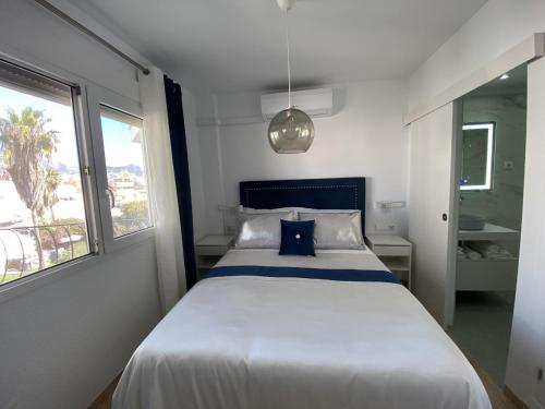 een slaapkamer met een groot wit bed en een blauw kussen bij Acapulco playa Nerja 407 planta superior in Nerja