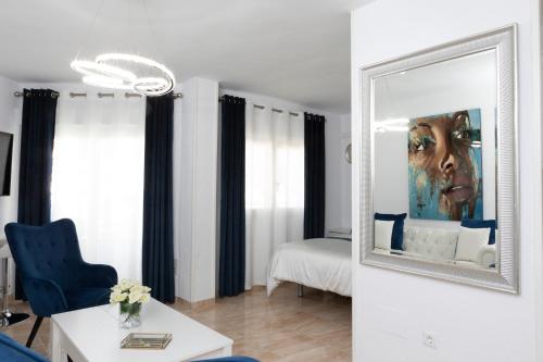 a living room with a mirror and a blue chair at Acapulco playa Nerja 407 planta superior in Nerja