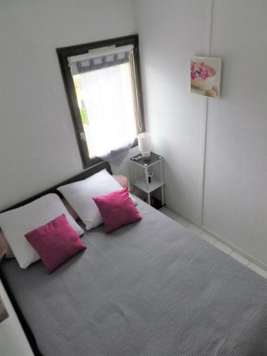 - une chambre avec un lit et 2 oreillers roses dans l'établissement T2 PLAGE DE LA CONQUE, au Cap d'Agde