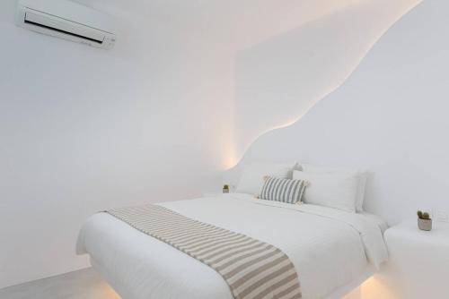 a white bedroom with a white bed and a white wall at Koumi Homes Mykonos in Elia
