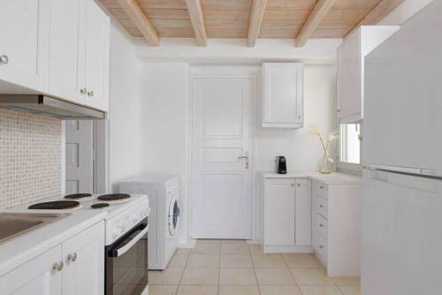 a kitchen with white cabinets and a stove top oven at Koumi Homes Mykonos in Elia