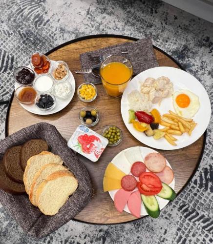 een houten tafel met borden met ontbijtproducten bij HOTEL ALMAZ PLAZA in Yakkasaray