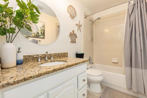 a bathroom with a sink and a toilet and a mirror at Heat of Siesta Village Walk to Beach w heated Pool in Siesta Key