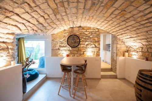 a kitchen with a table and a stone wall at La Grotte Bourguignonne, Terrasse extérieure in Dijon