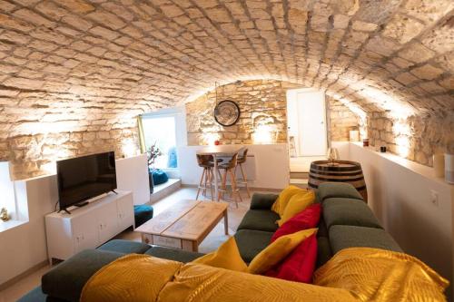 a living room with a couch and a tv at La Grotte Bourguignonne, Terrasse extérieure in Dijon